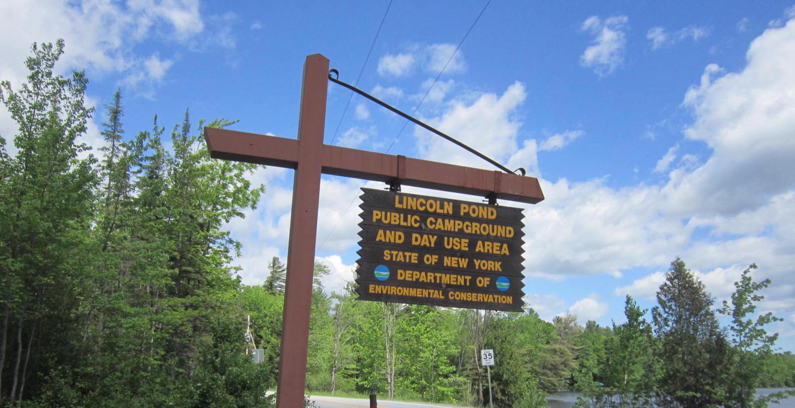 A yellow and brown sign marking a campground entrance.