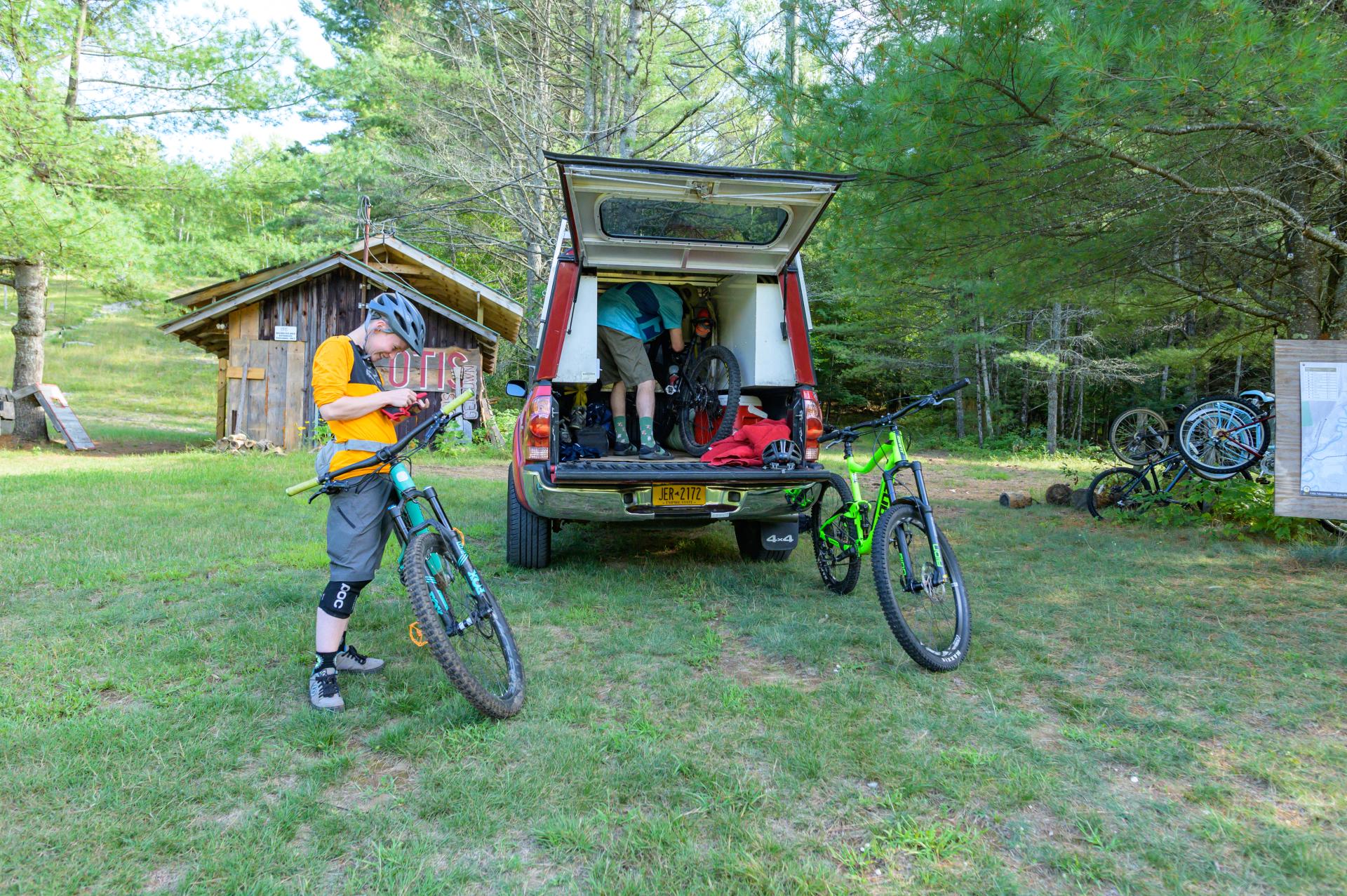 Two mountain bikers prep for a ride beside their vehicle