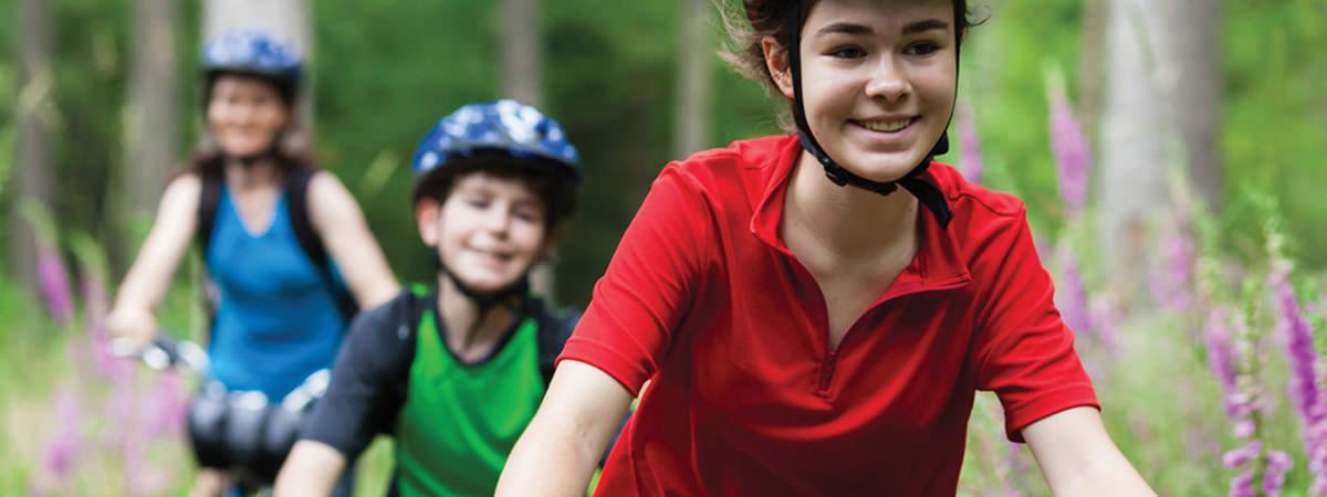 Smiling kids with helmets on bikes.
