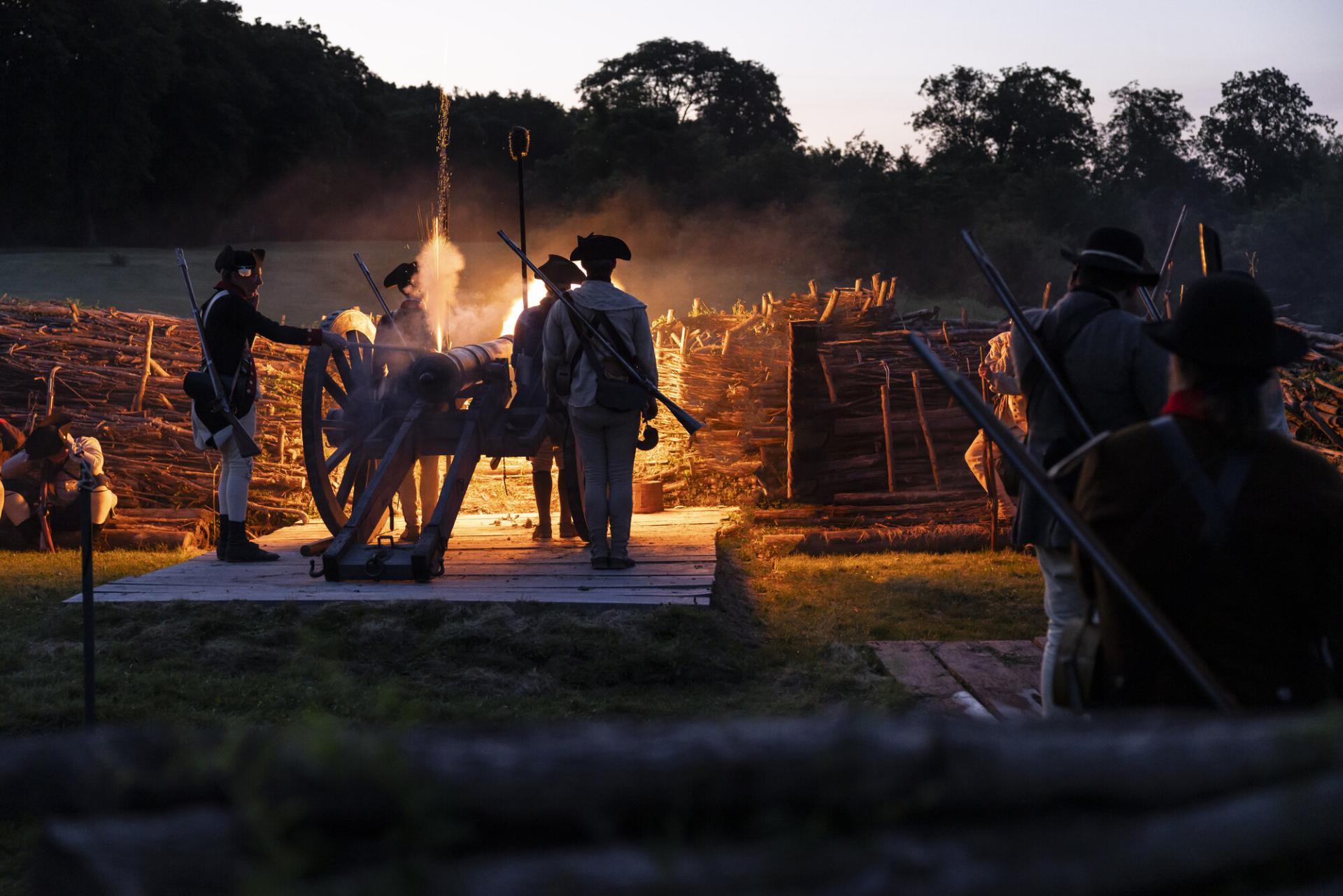 Reenactors cook a meal over a fire