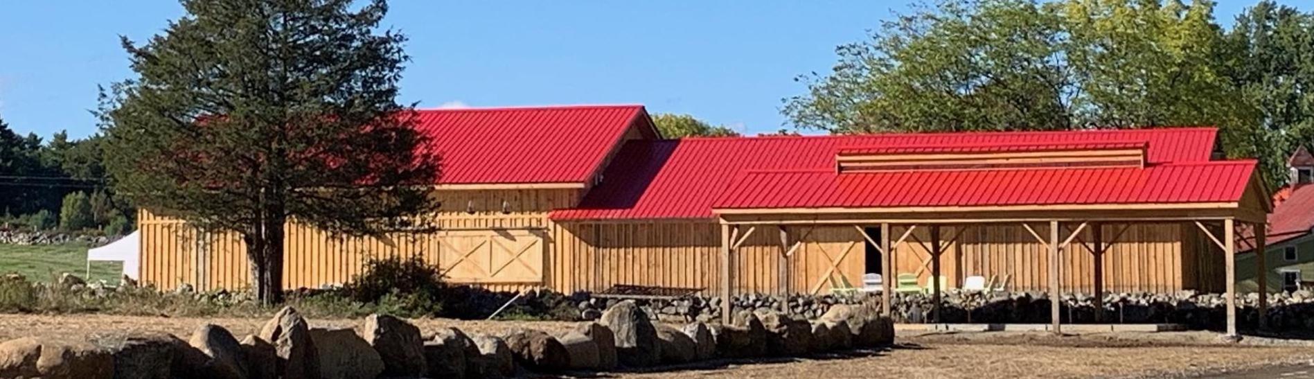 A wooden barn with red metal roof.