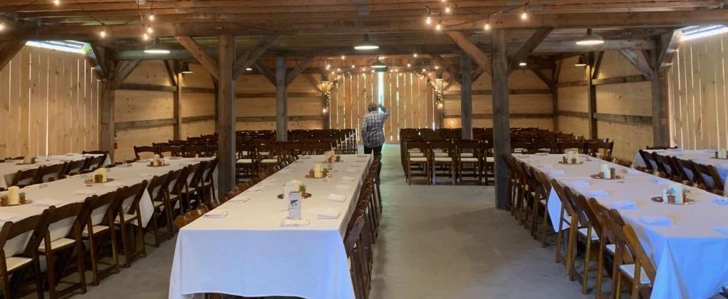 Long tables with white linens in the barn.