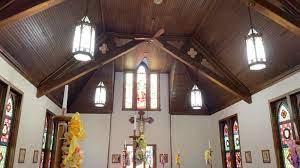 Tall ceiling with stained glass windows and long drop lamps in the church.