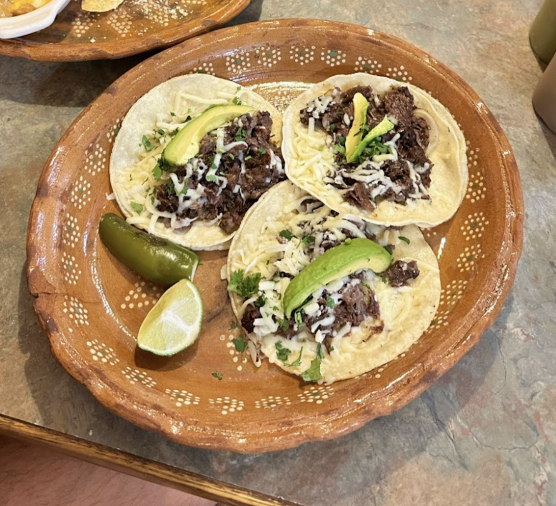 Three taco sit open faced on a plate.