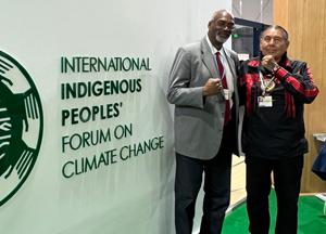 People standing in front of the International Indigenous Peoples Forum on Climate Change sign.