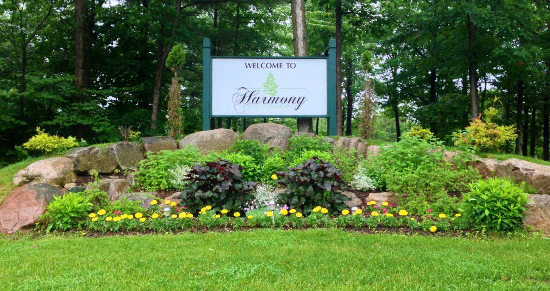 The front entry sign for Harmony Golf Club & Community with landscaping surrounding.