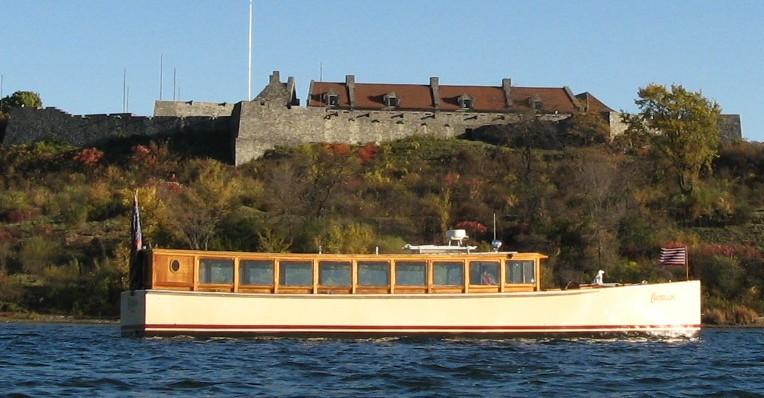A view from the water looking at the side of the Carillon boat with the wall of Fort Ticonderoga behind it.