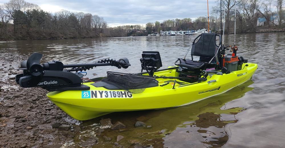 A green kayak fully fitted out with comfortable seat and fishing equipment.