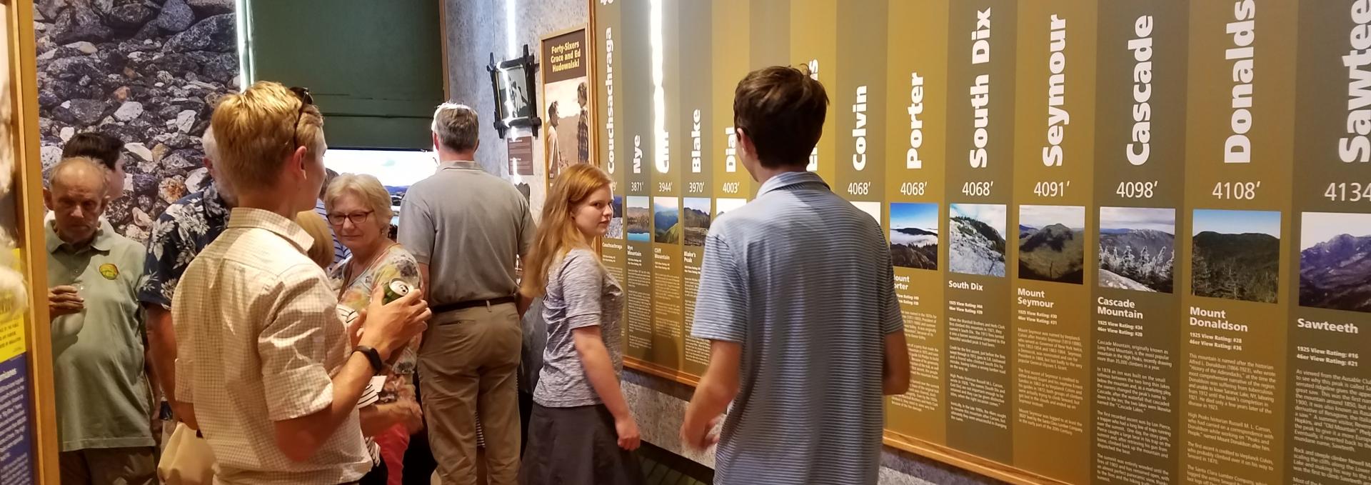 People look at a display discussing the high peaks.