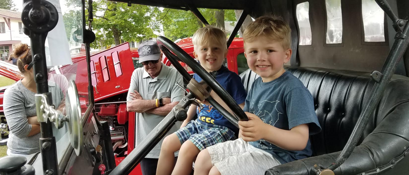 Smiling kids hold the steering wheel on equipment