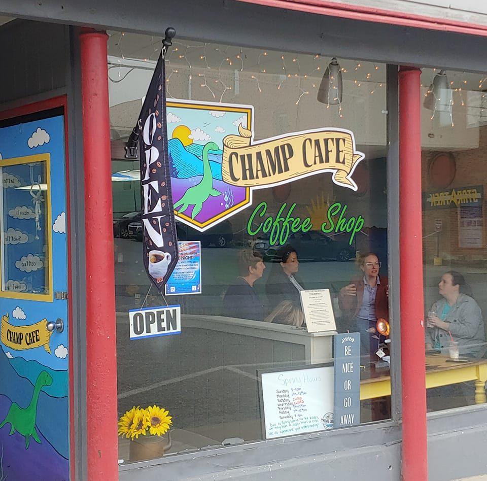 The exterior window art at the Champ Cafe with happy patrons at a table inside.