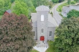 An aerial view of a tall stone church with red door.