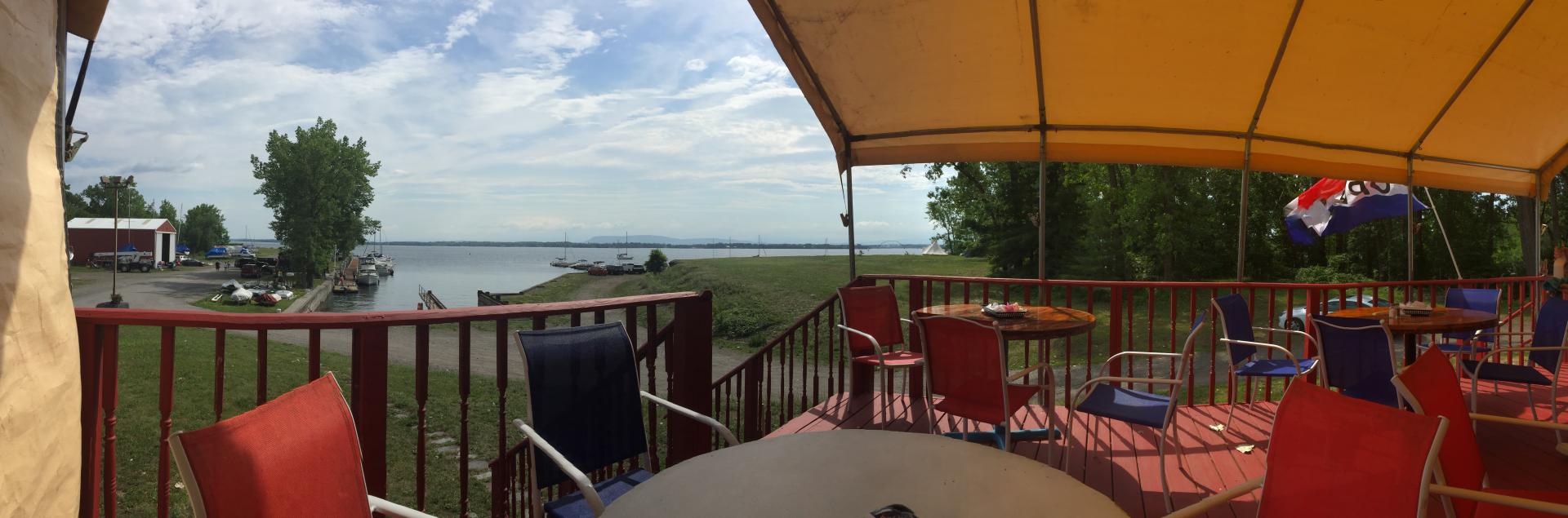 A covered porch with tables and chairs overlooking the marina.