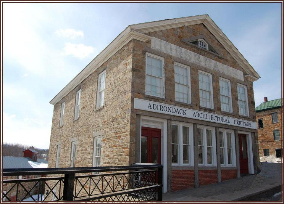 A tall stone building with white trim that houses the Adirondack Architectural Heritage.