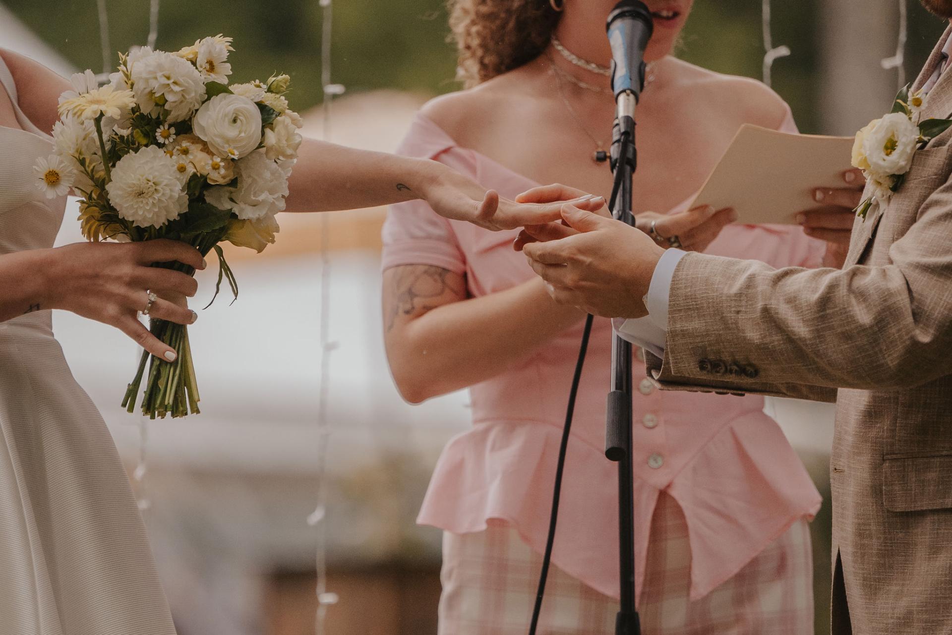 Bride holds a bouquet while she holds hands with the groom.