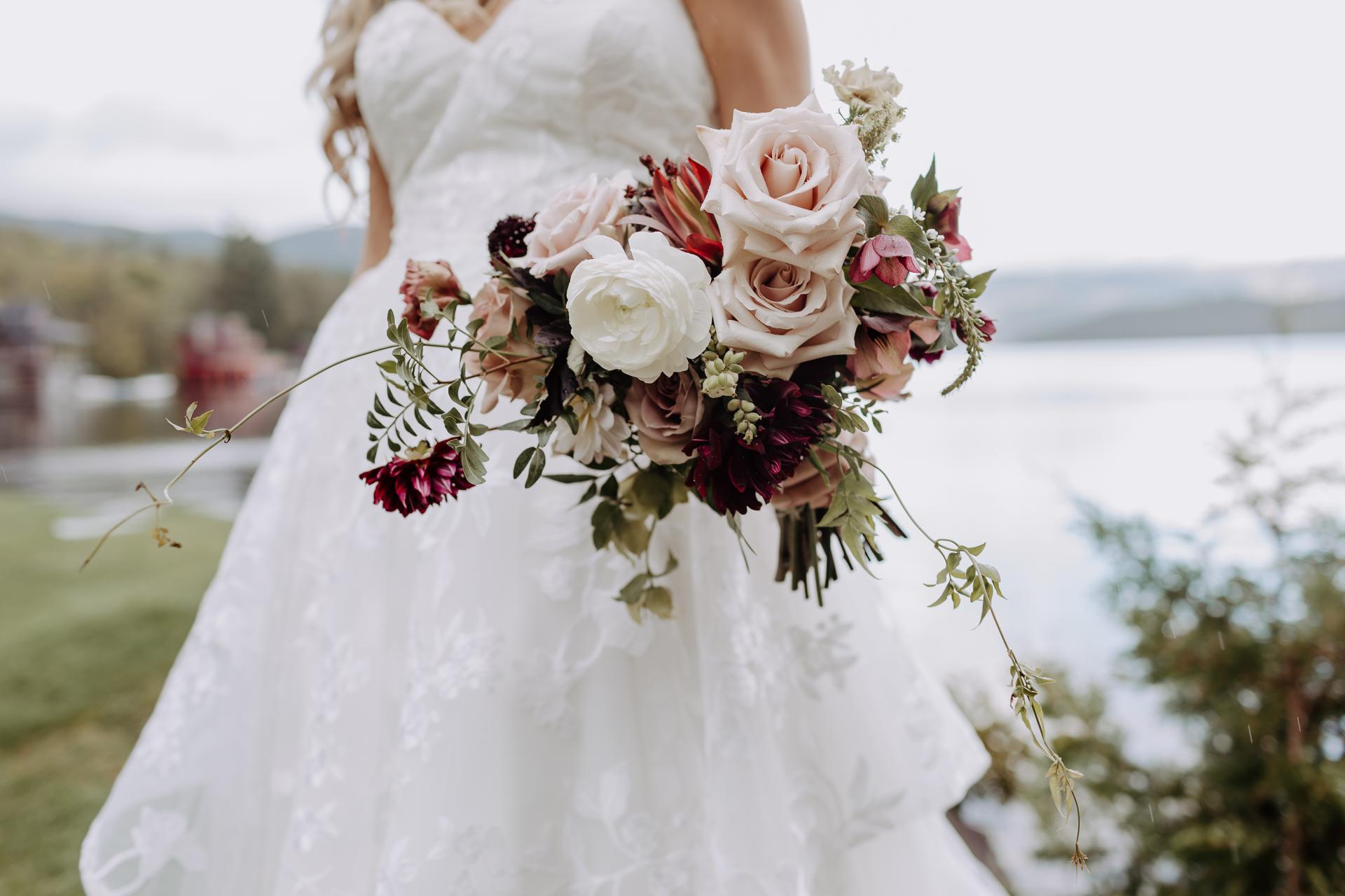 A woman in white walks by with a pink and white rose bouquet.