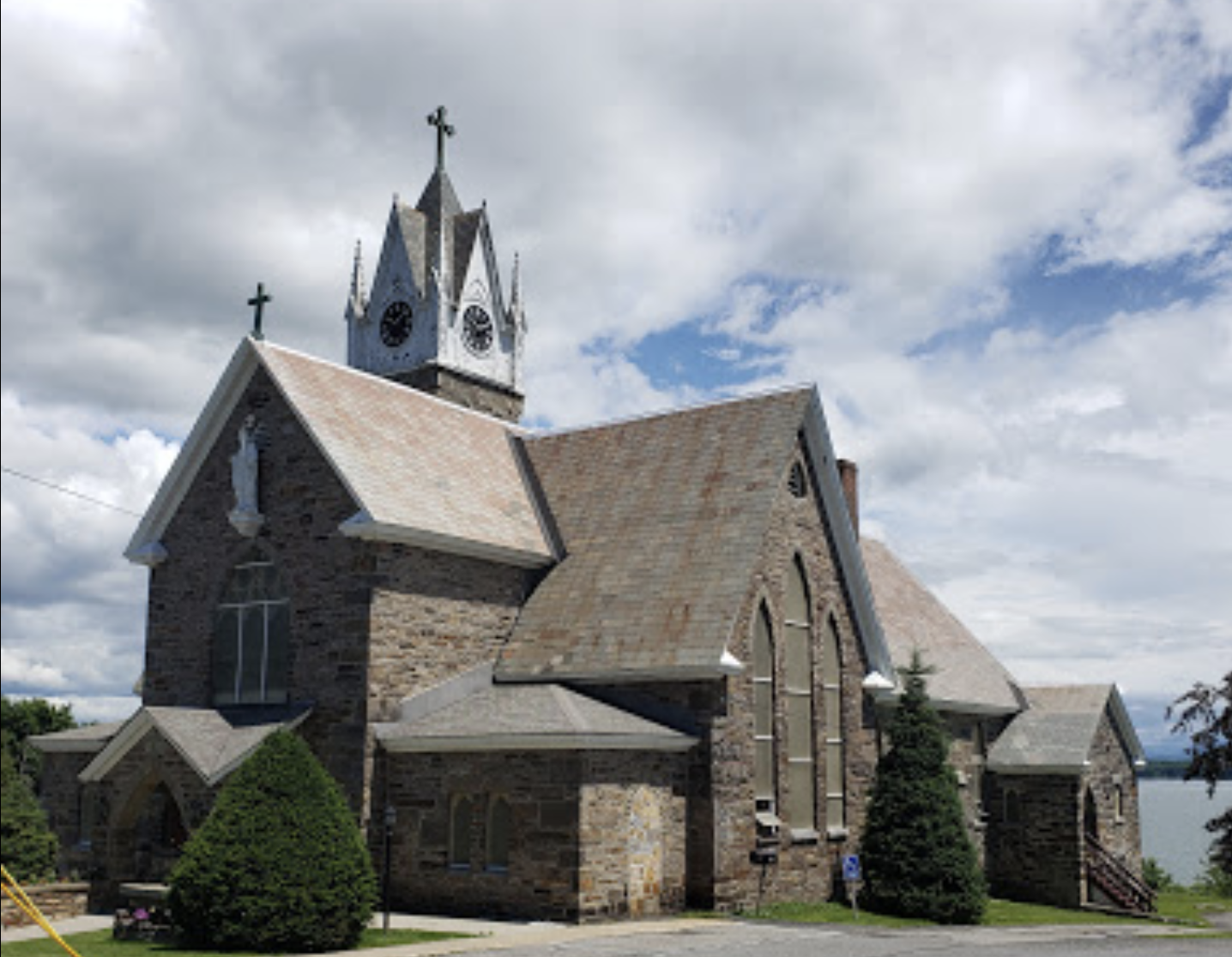 A tall stone church with many roofs and tall steeple.