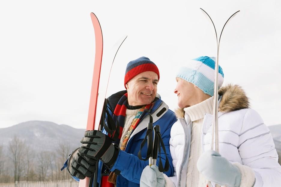 A smiling couple holding snow skis