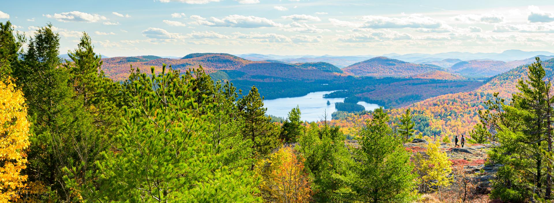 A large pond nestled among colorful fall mountains. 