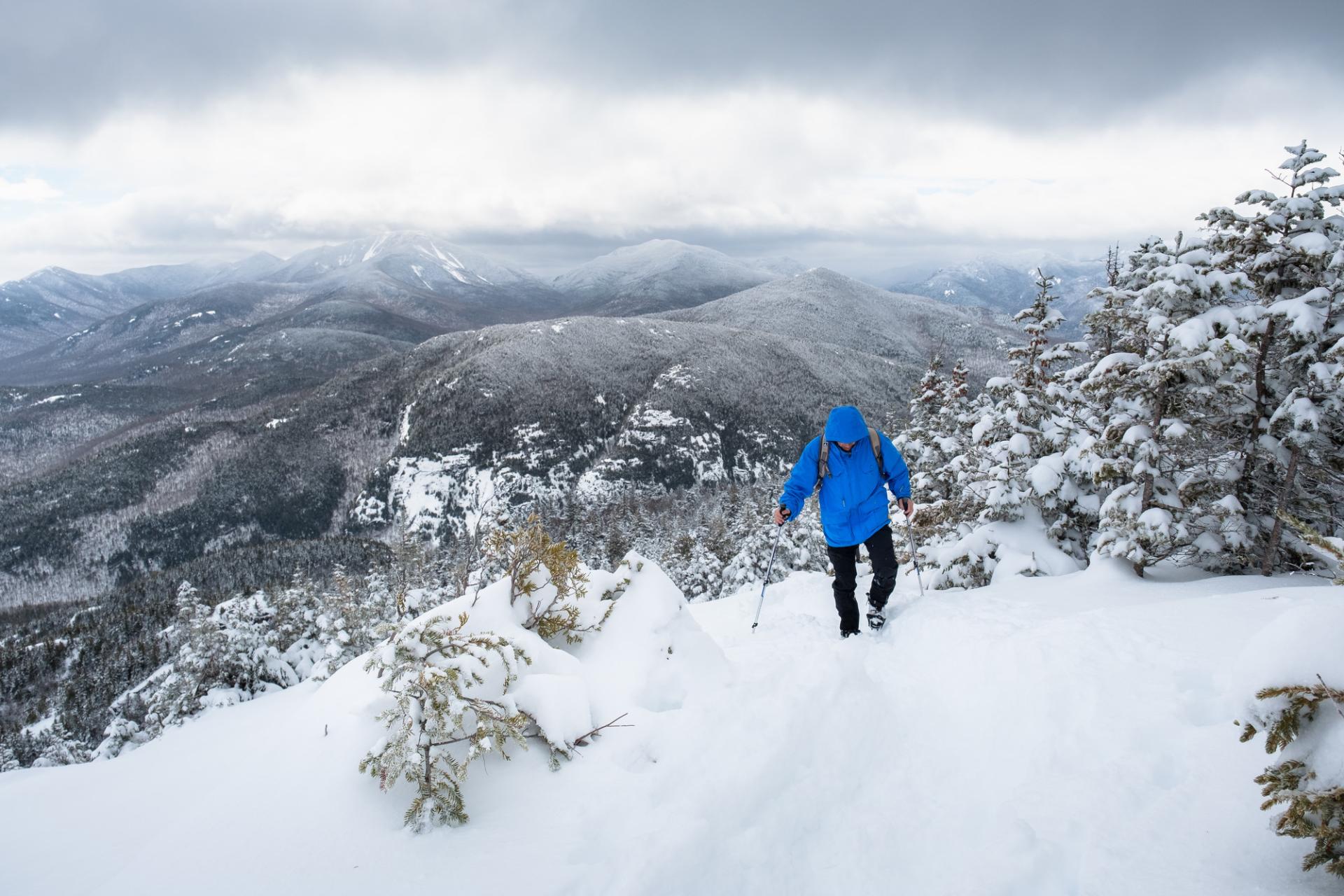A man walks up a snowy mountain trail