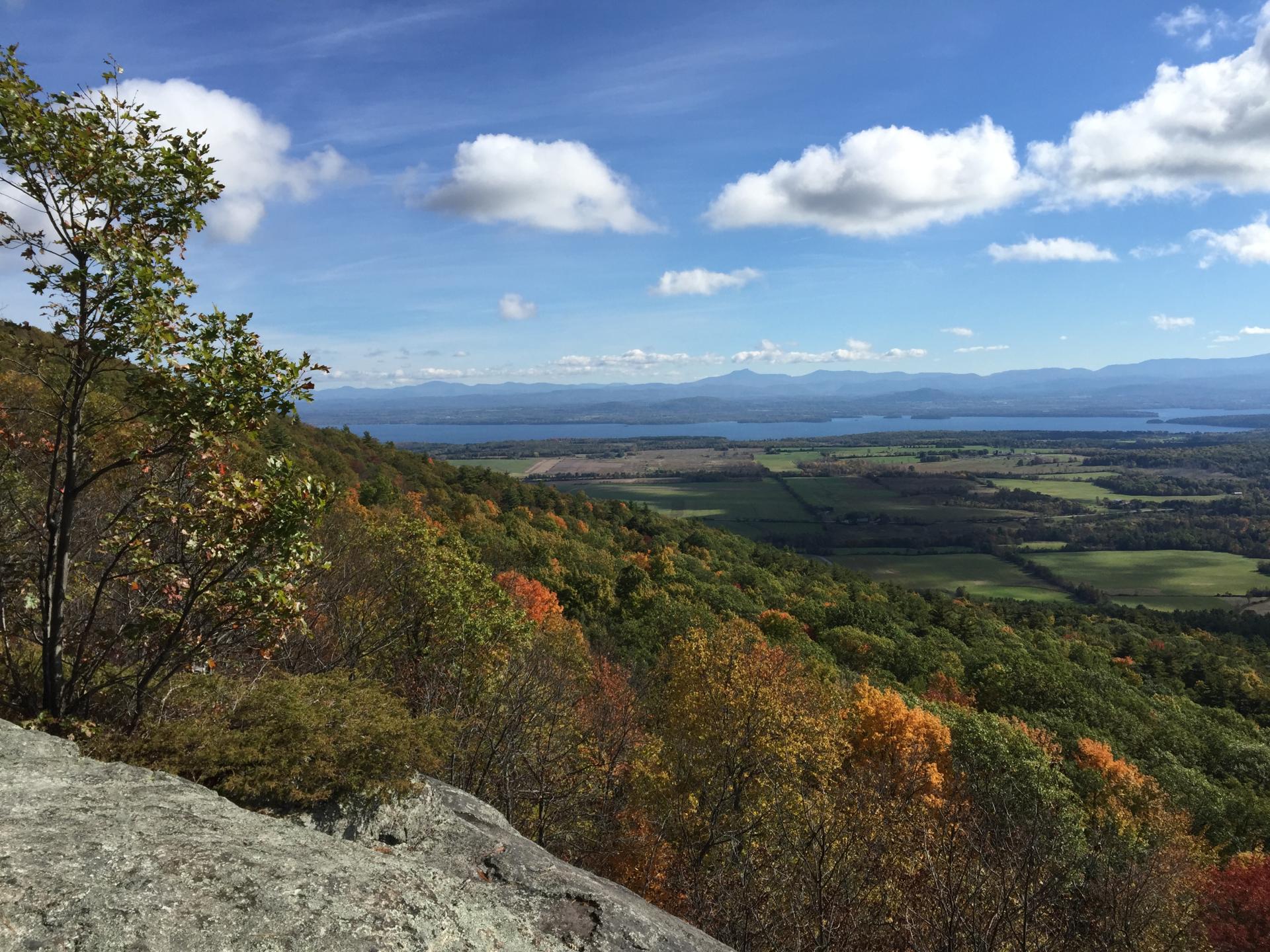 A fall view from a short peak of surrounding woods and a lake