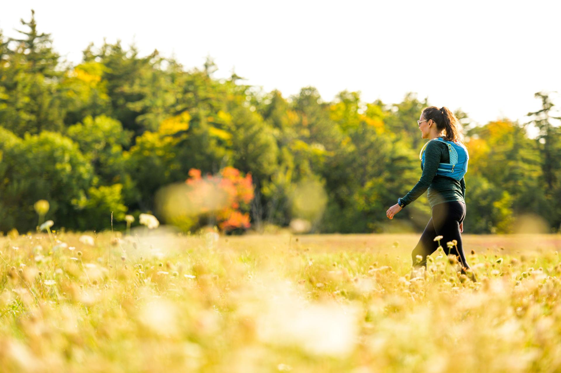A woman walks through a field of golden grasses