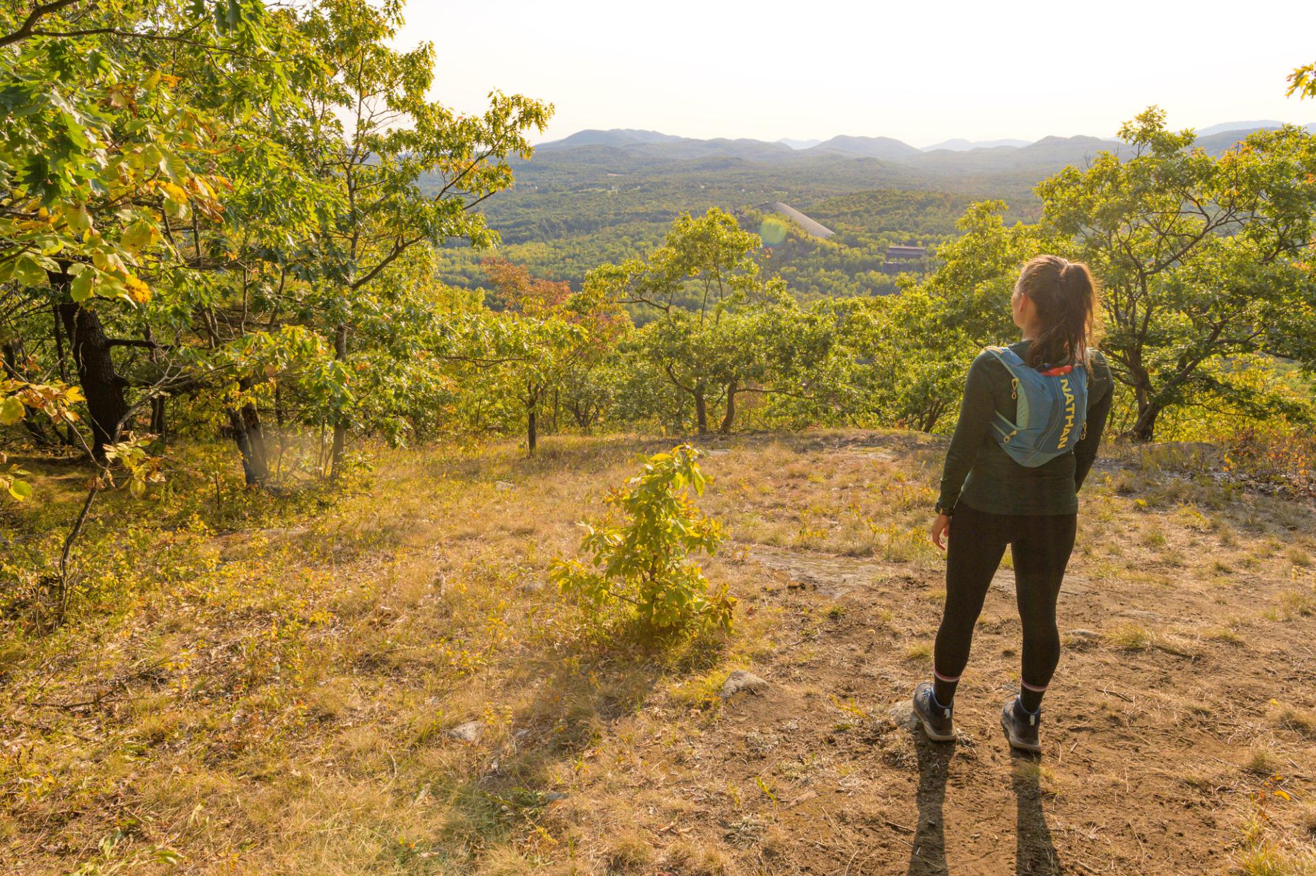 A woman looks at mountain views from an overlook