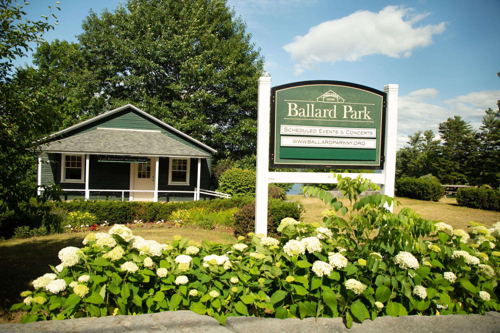 A sign for Ballard Park behind some white flowers