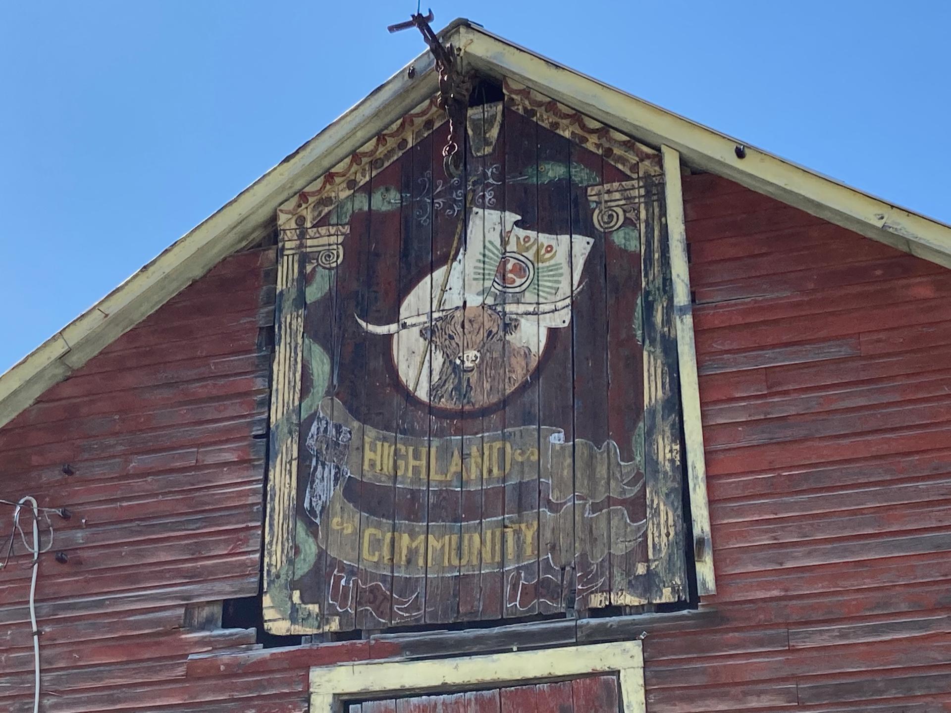 A barn with a Highland cow sign above the doors.