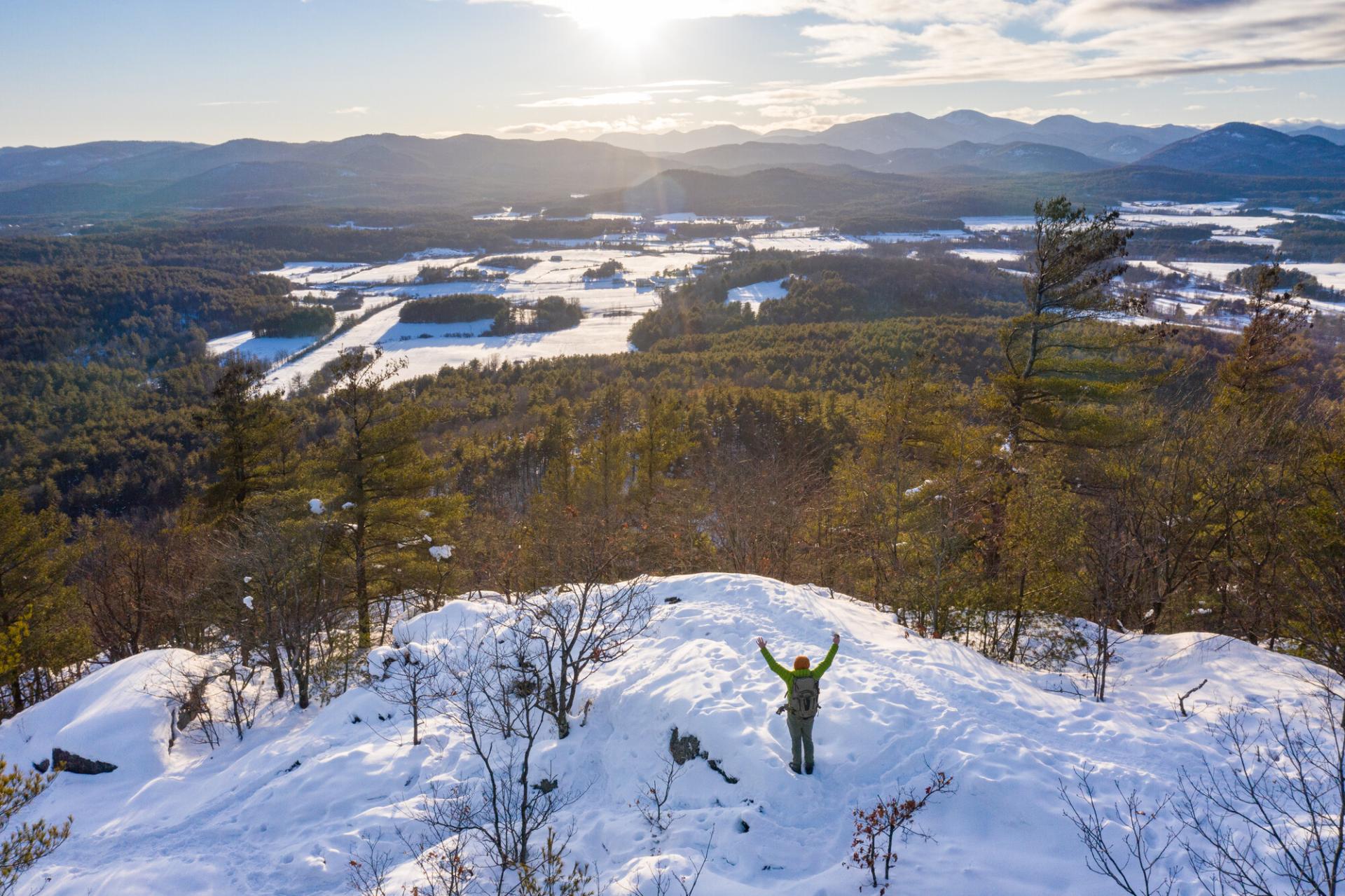 A person on the summit of Coon Mountain in the winter.