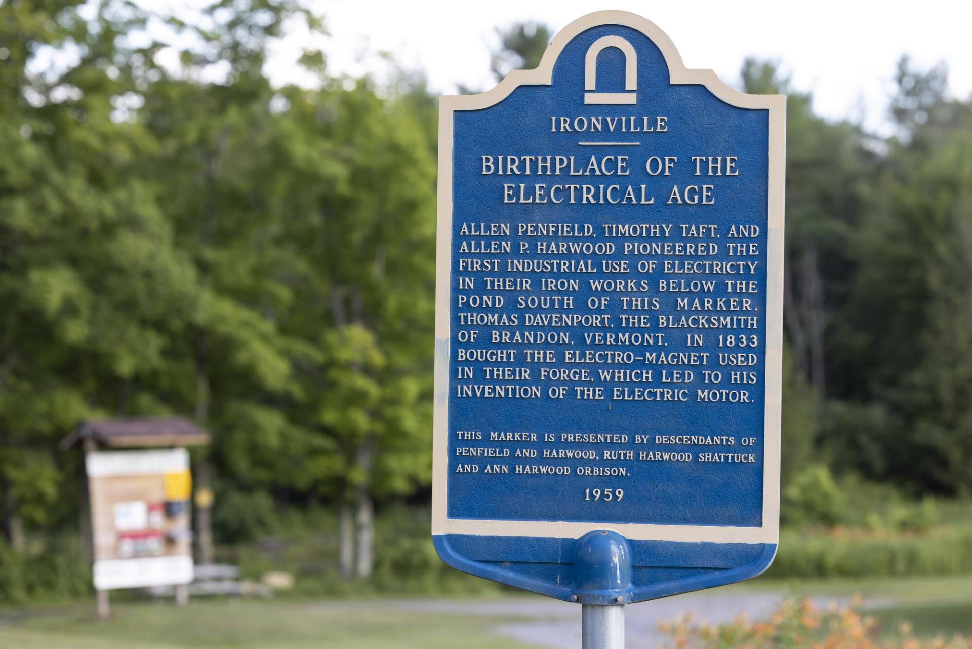 A blue metal sign for the Birth of the Electrical Age in Ironville