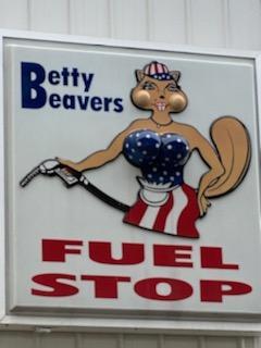 A large white sign with an illustrated beaver in a blue tube top and a white and red stripped skirt pumping gas.