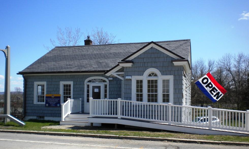 The entry to the grey building with white trim with entry ramp of the former bridge toll house