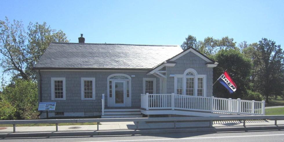 The entry to the grey building with white trim with entry ramp of the former bridge toll house