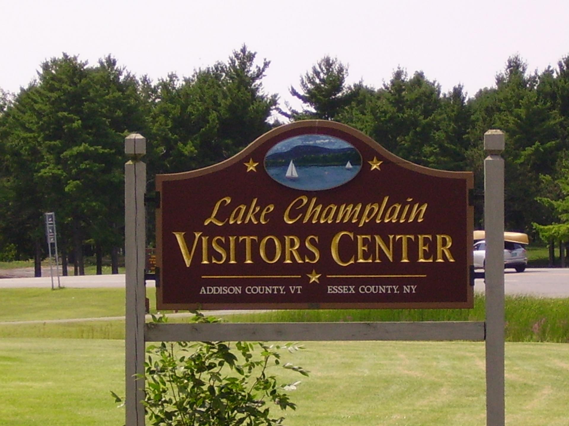 Sign for the Lake Champlain Visitors Center with gold lettering and dark stained background.