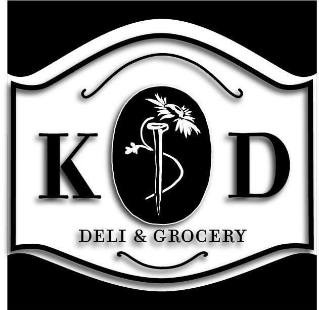 A curved plaque with K D Deli and Grocery with a daisy in the center.