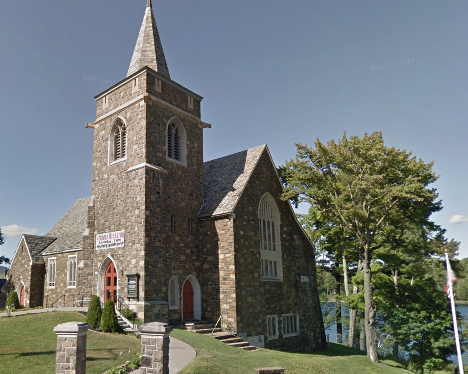 A tall stone church with high steeple on the banks of Mirror Lake.