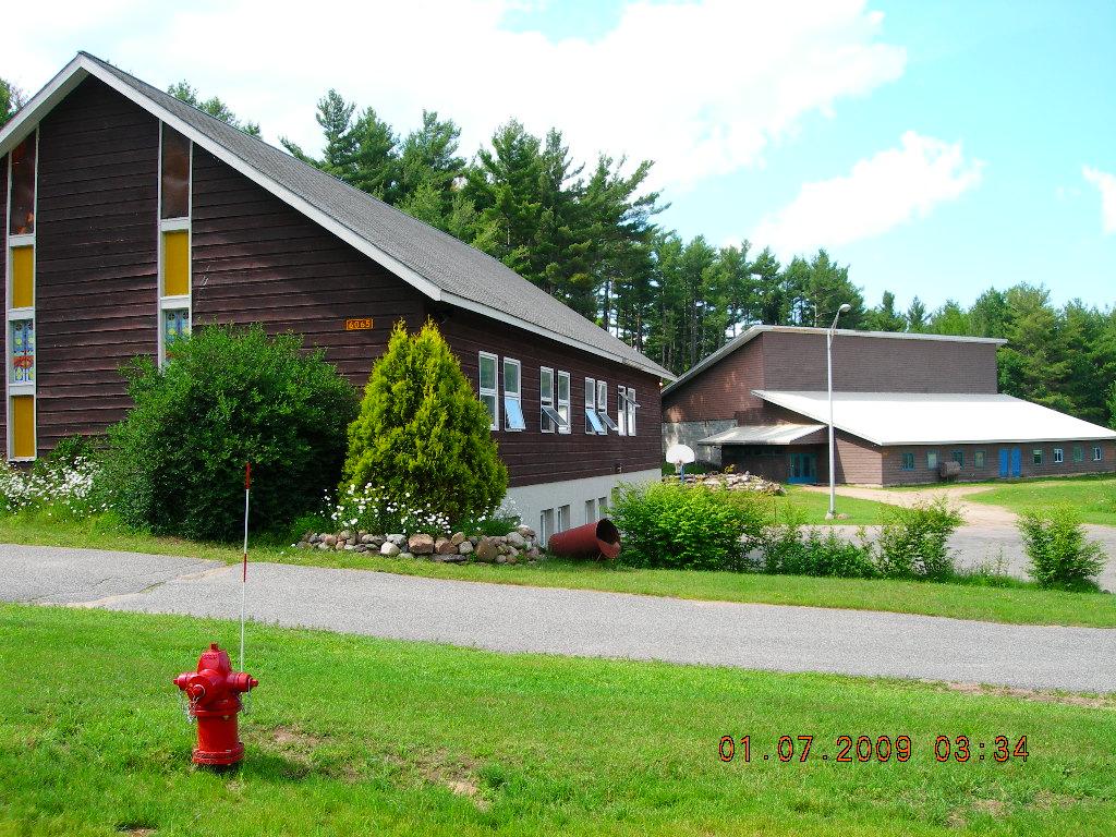 Exterior view of the lush grass and tall glass windows on the brown church.