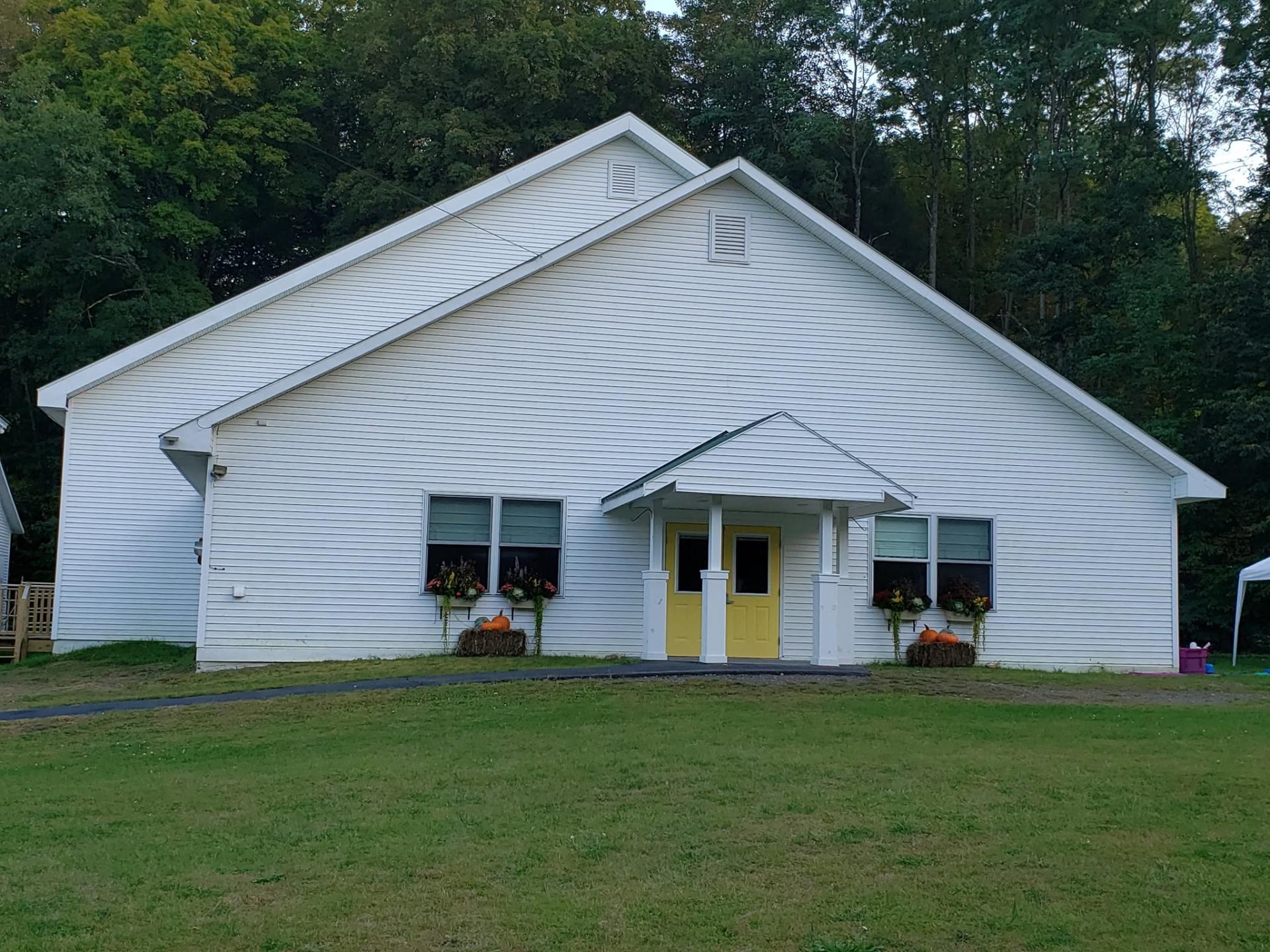 A white church with flower boxes and yellow doors.