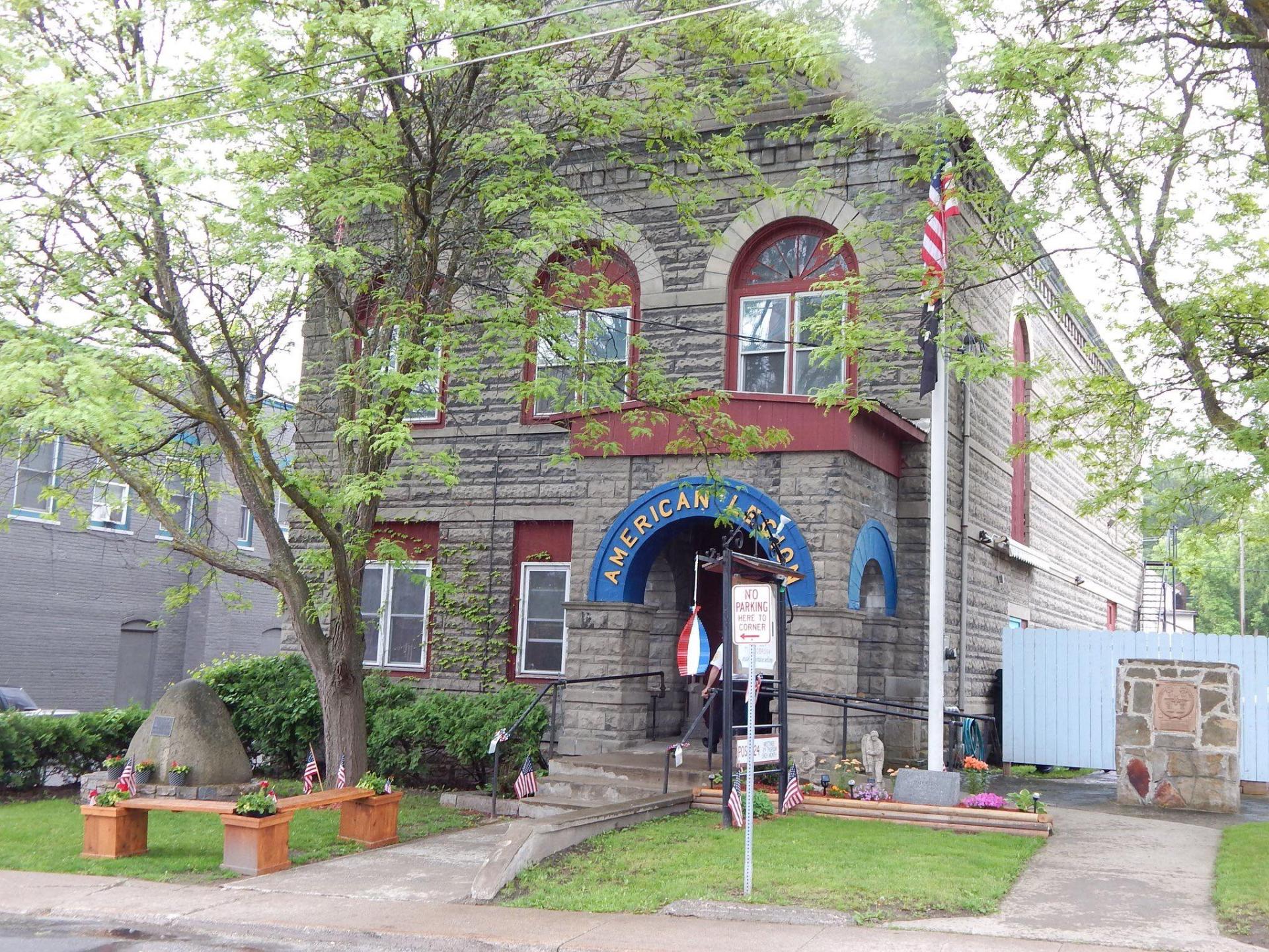 A grey stone building with red trim and a blue arched entry to the American Legion.