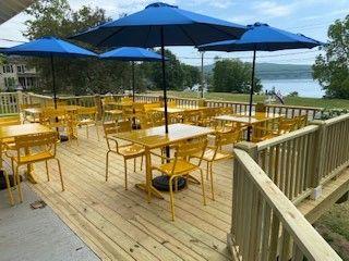 A huge deck with bistro tables and big blue umbrellas overlooking the lake.