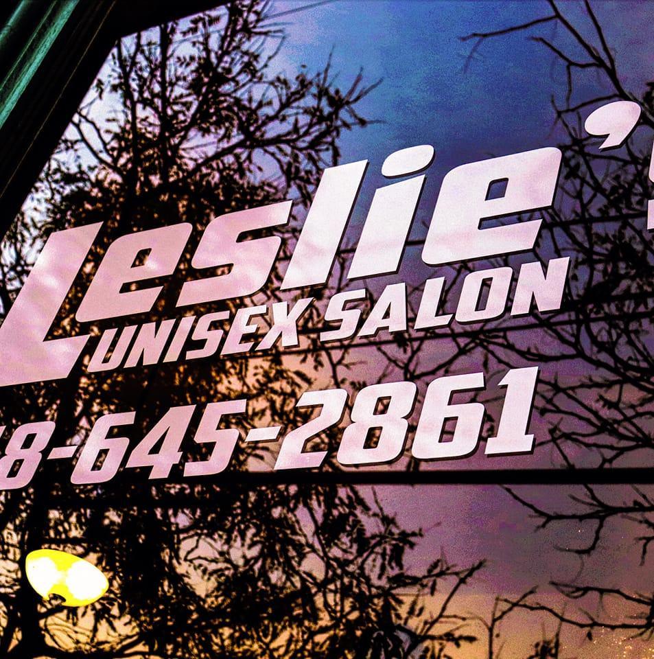 Window lettering at Leslies Unisex Salon reflecting a sunset.