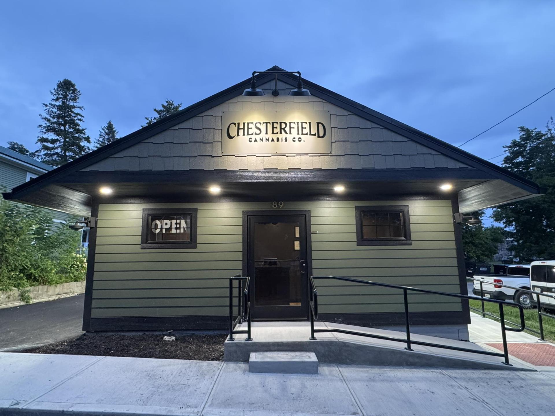 Exterior of the green and black building with concrete steps and ramp with metal handrail.