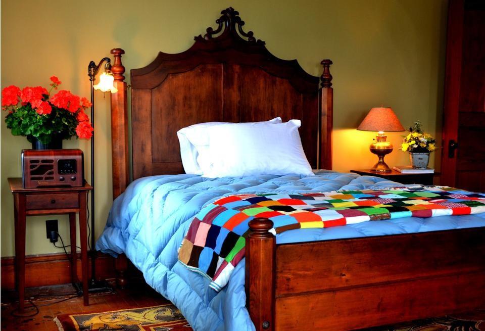 Quilts on the bed with ornate wooden headboard.