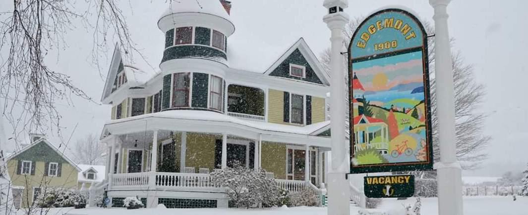 A historic home with covered porch blanketed in snow.