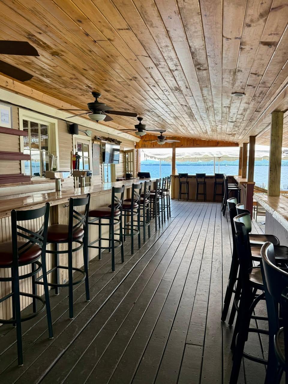 Looking down the bar on a covered porch at the open waters of Lake Champlain.
